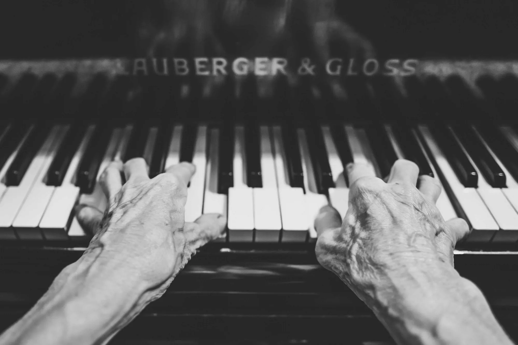 Black and white photograph of hands playing a grand piano