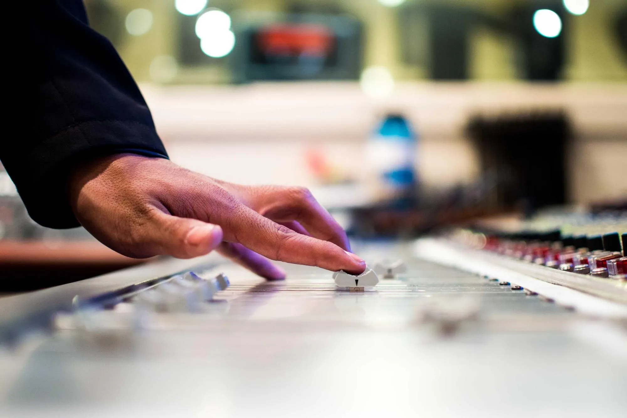 Hand adjusting faders on a mixing desk