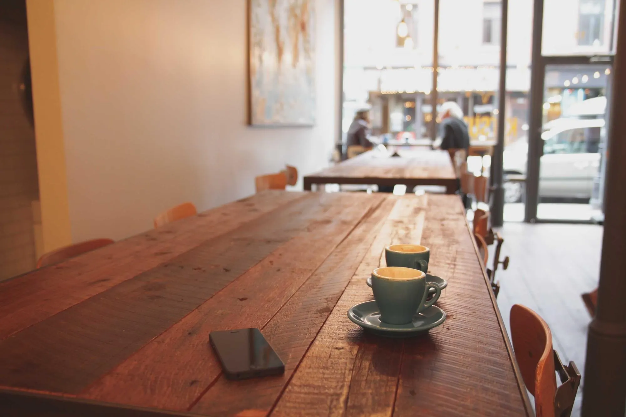 Wooden café table with a coffee cup in soft window light