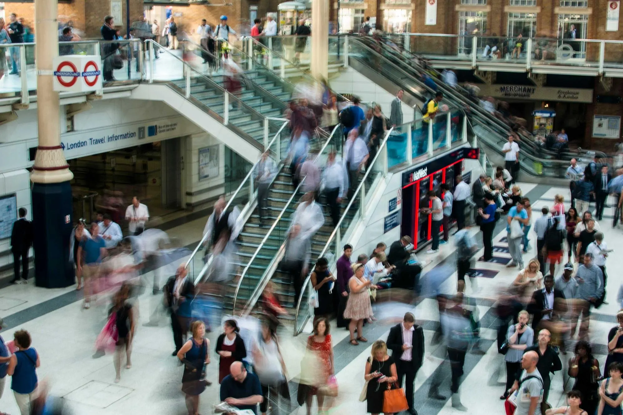 Busy concourse with blurred people moving between escalators