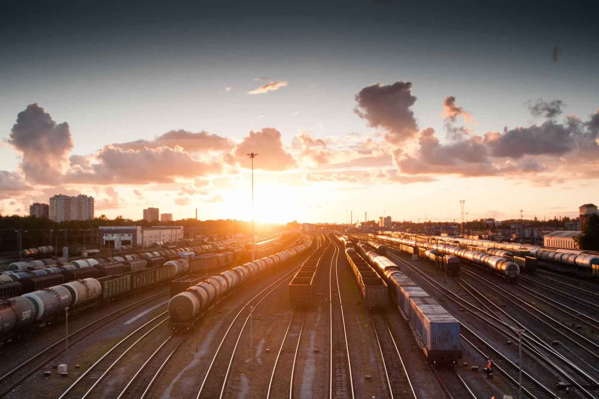 Rail yard with parked trains under an orange evening sky