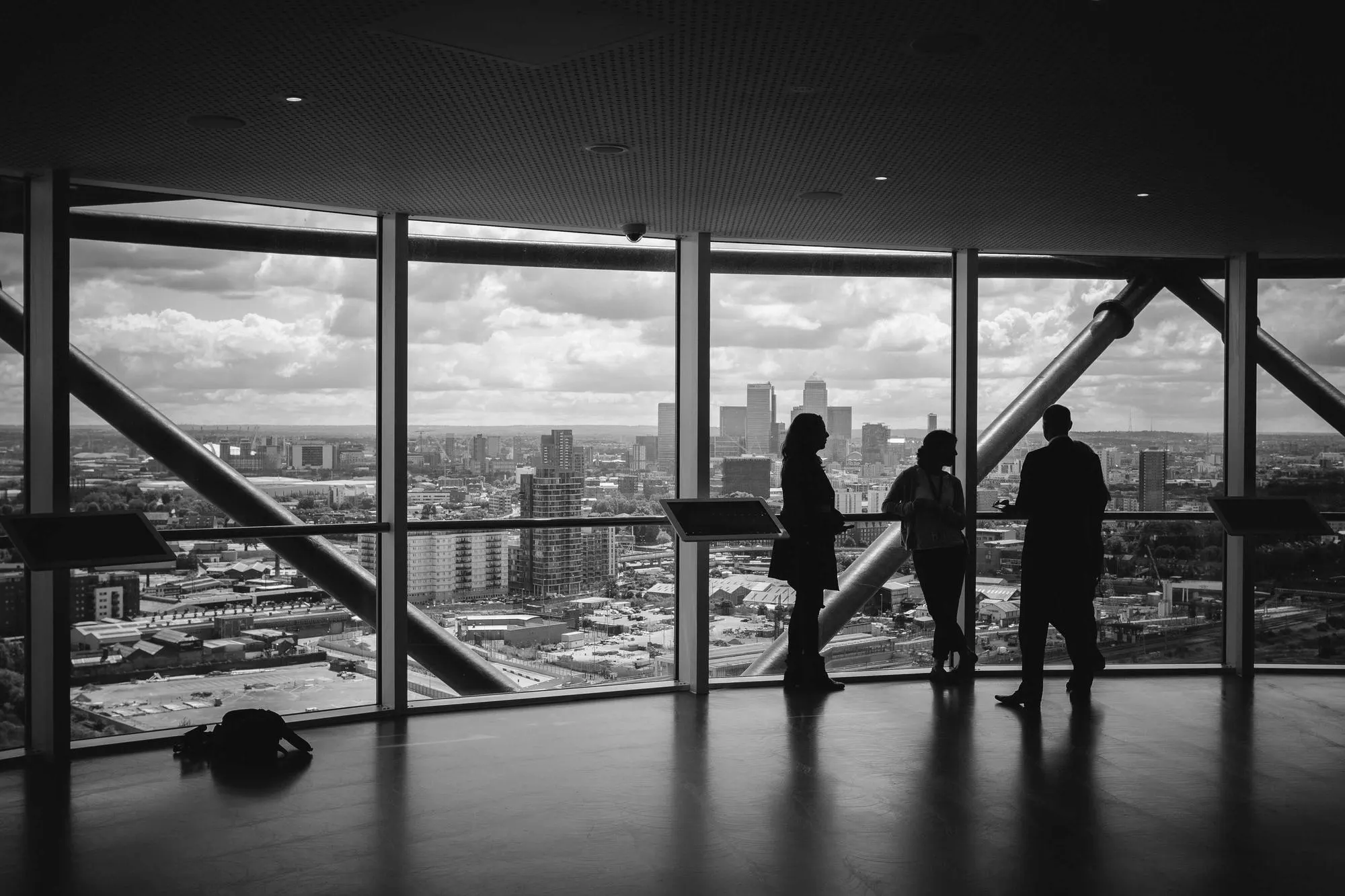 Black and white photograph of visitors at a floor-to-ceiling window