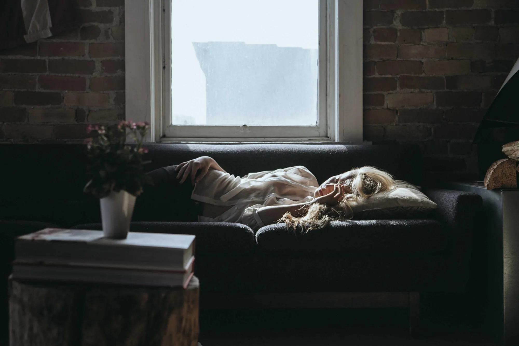 Someone resting on a sofa beneath a tall studio window